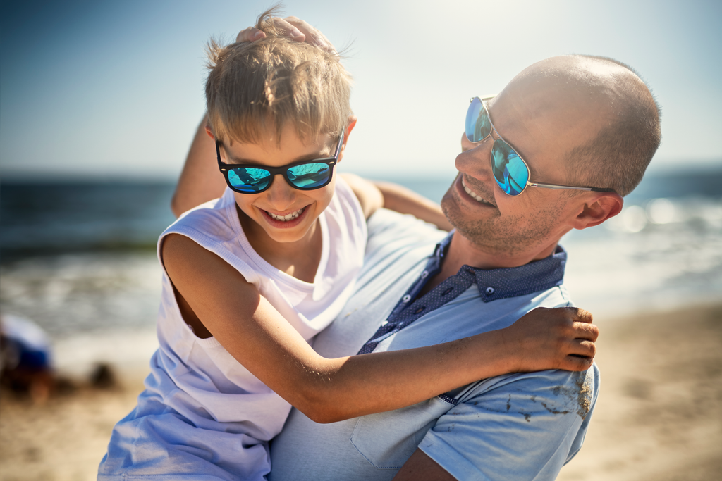 Father and son wearing sunglasses and smiling on the beach