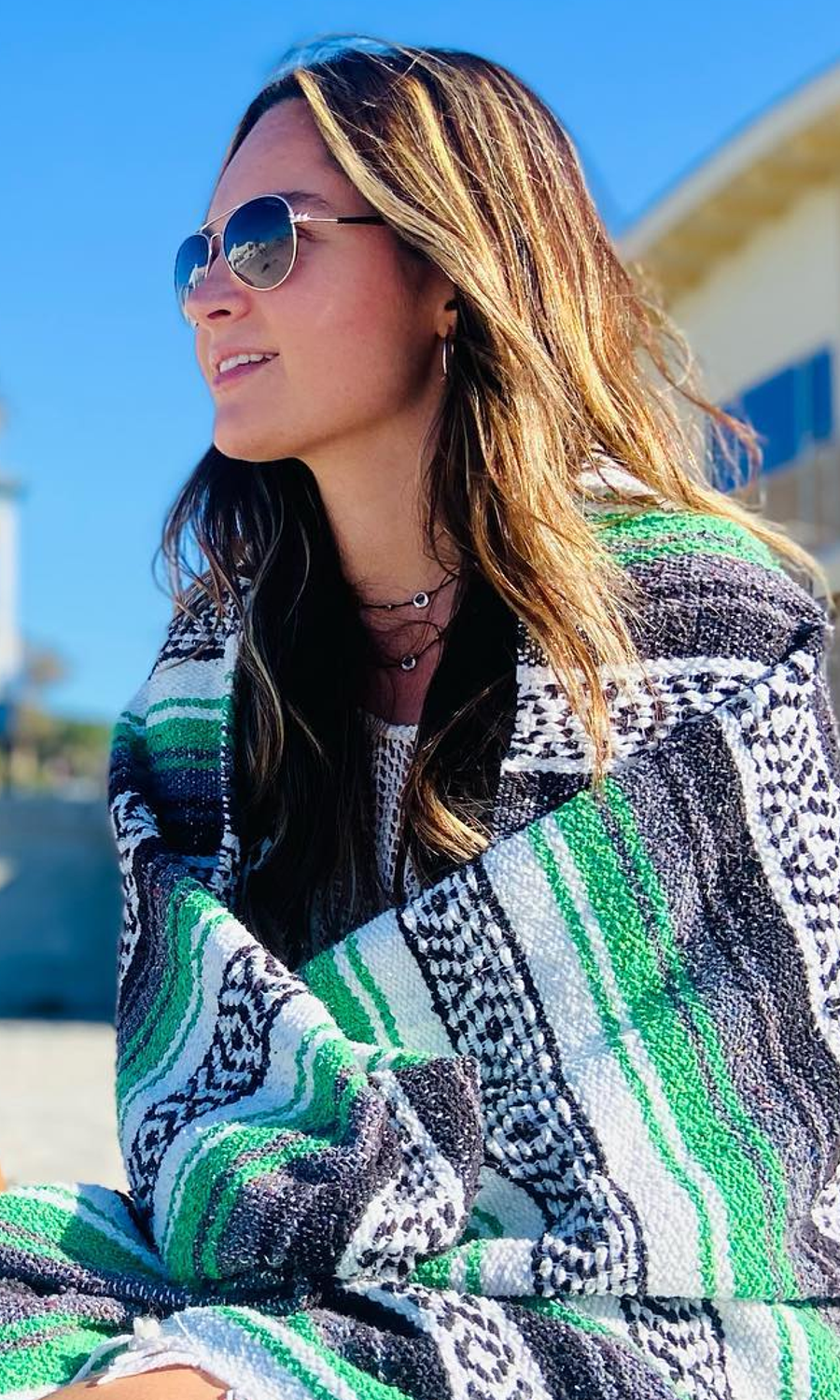 Woman wearing sunglasses wrapped in serape blanket.