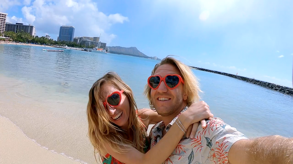 Woman and man wearing red heart shaped sunglasses on beach