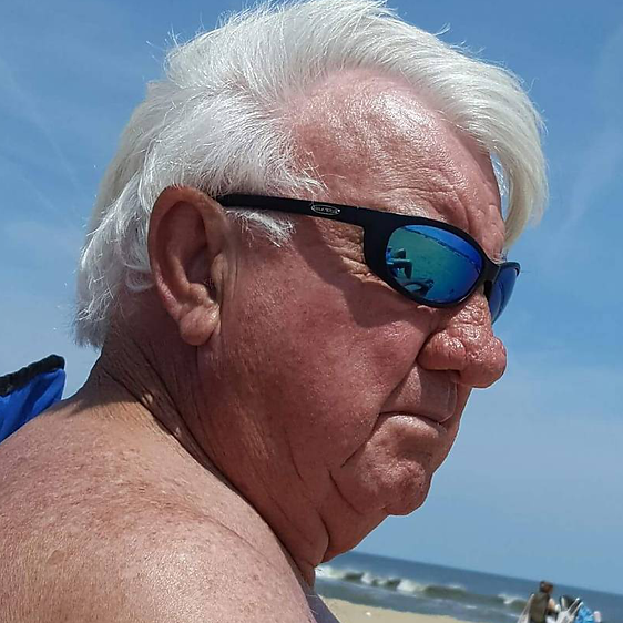 Man at the beach wearing Sea Striker Bridgetender polarized sunglasses in black frame with blue mirrored lenses