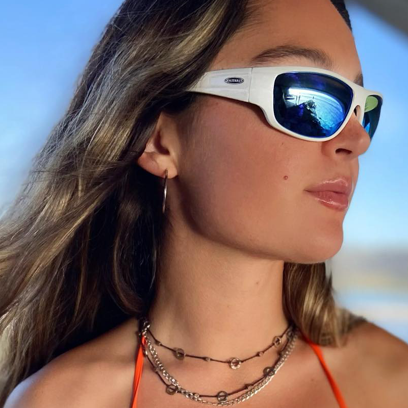 Model wearing Sea Striker Bill Collector polarized sunglasses in white frame with blue mirrored lenses