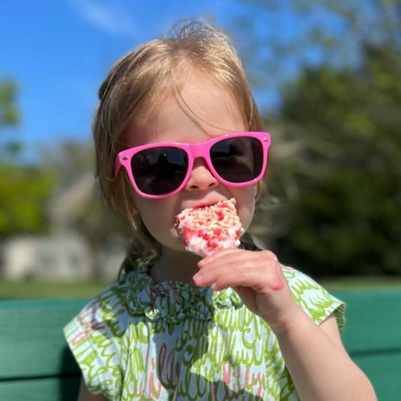 Toddler eating strawberry shortcake ice cream bar and wearing Just A Shade Smaller Whoop sunglasses