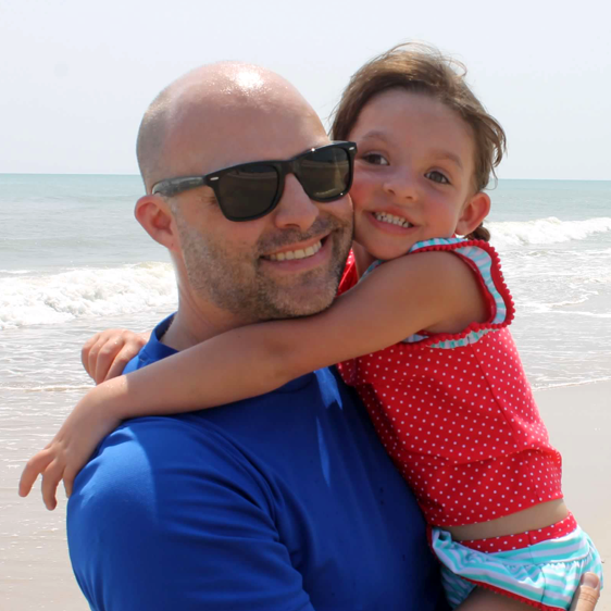 Man wearing Islander Eyes Azores polarized sunglasses, holding young girl on beach